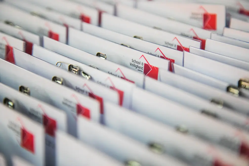 Een groep mappen met rood-witte knipsels, ter ondersteuning van scholen voor sociale veiligheid. School en Veiligheid