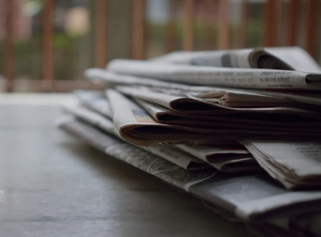 Een stapel kranten op een tafel, die ondersteuning biedt aan scholen bij sociale veiligheid. School en Veiligheid