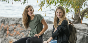 Twee meisjes zitten naast het water. School en Veiligheid