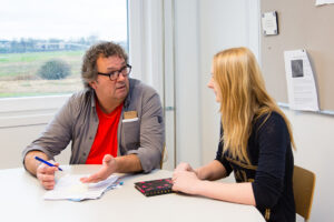 Een man en een vrouw zitten aan tafel tijdens een pestenactie in het mbo. School en Veiligheid