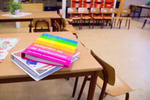 Een boek op tafel in een klaslokaal, waarin de problematiek van pesten in het primair onderwijs wordt onderzocht. School en Veiligheid