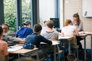 Een groep studenten die in een klaslokaal aan een bureau zitten en last hebben van pesten tijdens het voortgezette onderwijs. School en Veiligheid
