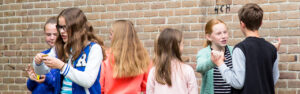 Een groep mensen die naast een bakstenen muur in het basisonderwijs staat en leert over seksualiteit. School en Veiligheid