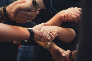 Een groep mensen die zich bezighoudt met Dialoog onder Druk, hand in hand in een cirkel. School en Veiligheid