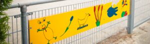 Een geel bord op een hek waarschuwt voor seksuele grensoverschrijding in het primair onderwijs. School en Veiligheid