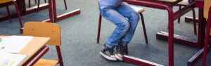 Een jongen die aan een bureau in een klaslokaal zit en seksuele grensoverschrijding ervaart in het primair onderwijs. School en Veiligheid