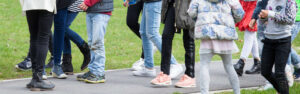 Een groep kinderen staat in een rij in een park en onderzoekt passende grenzen en sociale interacties binnen de context van het basisonderwijs. School en Veiligheid