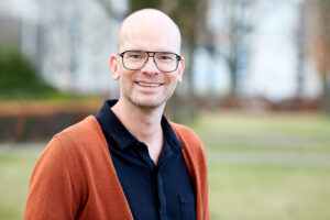 Een kale man met bril lacht tijdens De Gouden en Zilveren Weken in een park. School en Veiligheid