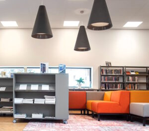 Het interieur van een bibliotheek met oranje banken en boekenplanken die scholen bij sociale veiligheid ondersteunt. School en Veiligheid