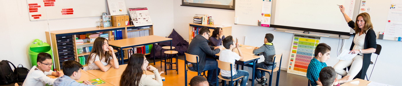 Een groep mensen die aan een bureau in een klaslokaal een discussie voeren over de vrijheid van meningsuiting en radicalisering. School en Veiligheid