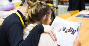 Een man en een vrouw lezen samen in een klaslokaal een tijdschrift en onderzoeken het onderwerp Seksuele grensoverschrijding in het mbo. School en Veiligheid