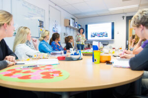 Een groep mensen die rond een ronde tafel zitten en discussiëren over omgaan met seksualiteit in het mbo. School en Veiligheid