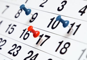 Een kalender met rode en blauwe speldjes erop, perfect voor het ordenen van je agenda. School en Veiligheid