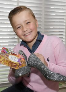 Een jonge jongen, ik ben, die een paar zilveren glitterschoenen vasthoudt. School en Veiligheid