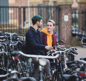 Twee mannen ondersteunen fietsen op een parkeerplaats. School en Veiligheid