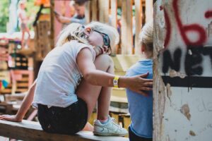 Twee jonge meisjes zitten op een bankje op een festival en krijgen steun voor sociale veiligheid. School en Veiligheid