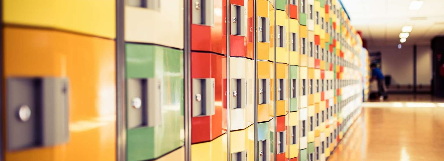 Levendige kluisjes in een gang met posters van Werken aan seksueel integer gedrag van schoolmedewerkers. School en Veiligheid