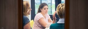 Een diverse groep mensen, waaronder individuen met verschillende genderidentiteiten en seksuele geaardheden, zitten rond een tafel in een vergaderruimte. School en Veiligheid