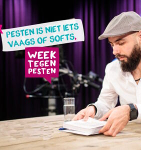 Een man met een baard die aan tafel een boek leest en scholen actief ondersteunt bij het bevorderen van de sociale veiligheid. School en Veiligheid