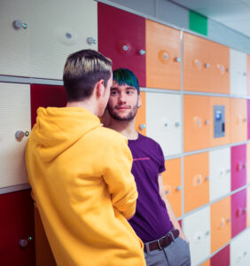 Twee mannen ondersteunen scholen bij het bevorderen van sociale veiligheid in een kleedkamer. School en Veiligheid