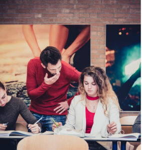 Een groep mensen die aan een tafel zit in een klaslokaal, ondersteund door sociale veiligheidsmaatregelen. School en Veiligheid