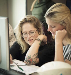 Twee vrouwen zitten achter een computer en ondersteunen scholen bij het bevorderen van de sociale veiligheid. School en Veiligheid