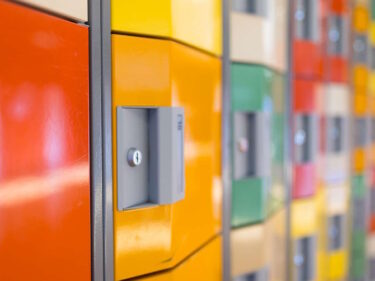 Kleurrijke kluisjes in een schoolgang, ondersteunt scholen bij sociale veiligheid. School en Veiligheid