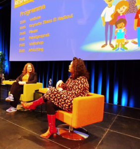 Twee vrouwen zitten op stoelen voor een scherm en bieden ondersteuning aan scholen met sociale veiligheid. School en Veiligheid