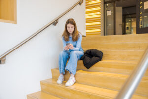 Meisje op een trap. Verdrietig en met mobieltje in de hand.